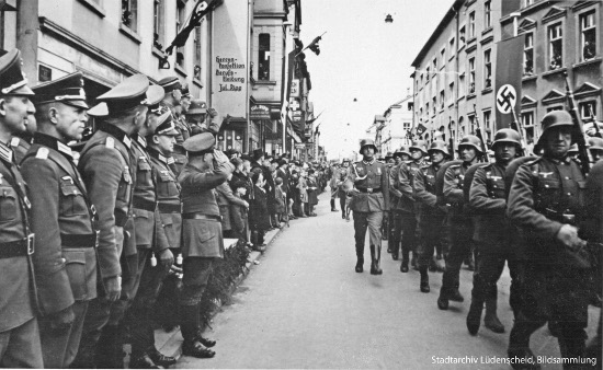 Foto: Parade der Wehrmacht durch die Knapper Str.. Im Hintergrund die Werbung des jüdischen Bekleidungsgeschäftes Jul. Ripp.